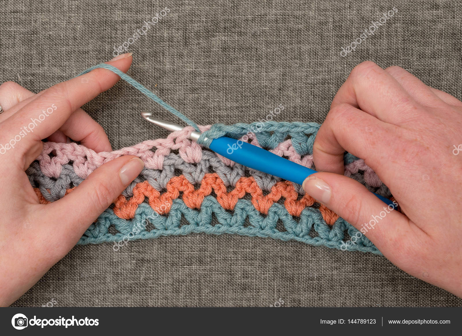 Hands Knitting Hook and Crocheted Band with Wavy Color Pattern